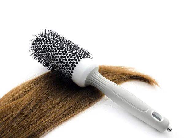 理发店的梳子和头发被白色的背景隔开了 一种白色梳子和棕色头发的组合 专业的理发刷 女性头发 — 图库照片