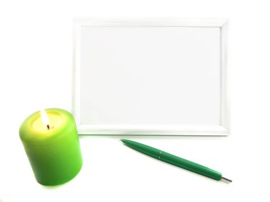 Beyaz fotoğraf çerçevesi, yeşil mum ve beyaz arka planda izole edilmiş yeşil kalem. Modern bir fotoğraf çerçevesi, mum ve kalemin bileşimi. Ev dekorasyonu için çerçeve ayarla.