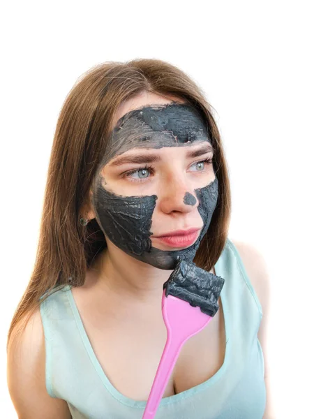 白い背景に粘土や泥のマスクと化粧ブラシを持つ女性 粘土マスクとメイクブラシで顔 黒化粧品マスク — ストック写真