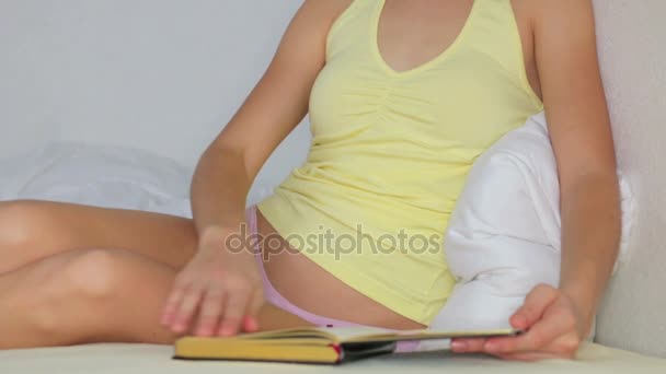 Szép, fiatal lány, egy ágyon könyvet olvas — Stock videók