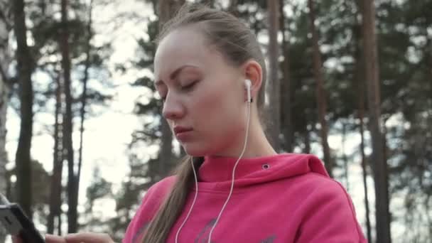 女孩戴上耳机，打开音乐 — 图库视频影像