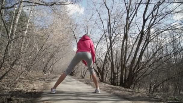 Девушка-спортсмен растягивается в парке перед бегом — стоковое видео