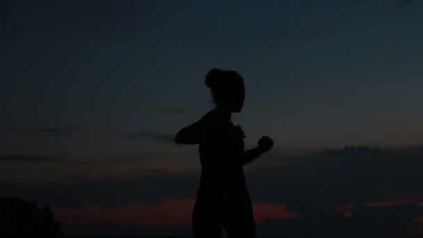 Menina faz ioga ao pôr do sol no topo de uma montanha — Vídeo de Stock