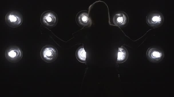 Silhueta de uma menina dançando sobre as luzes de fundo. Movimento lento — Vídeo de Stock