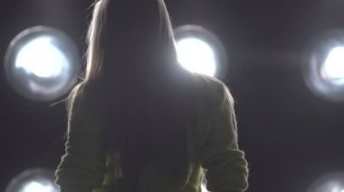 Arka plan ışığı dans bir kız silüeti.