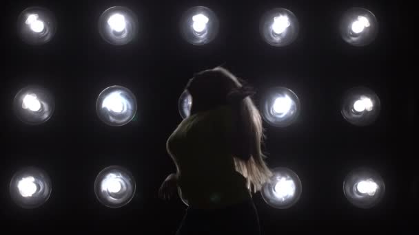 Silhuetten av en flicka dansa på bakgrunden belysningen. — Stockvideo