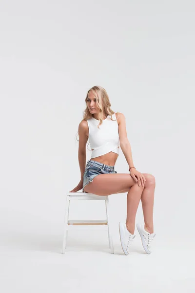 Дівчина з ідеальним тілом в джинсових шортах на білому тлі — стокове фото