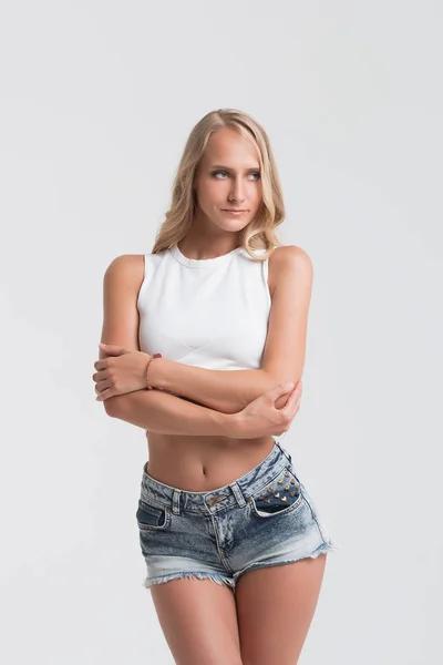 Chica con el cuerpo perfecto en pantalones cortos de mezclilla sobre fondo blanco —  Fotos de Stock