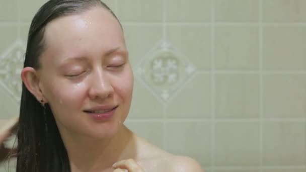 The girl washes her hair in the shower — Stockvideo