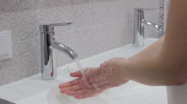 Suyun altında sabunla ellerini yıkamak.