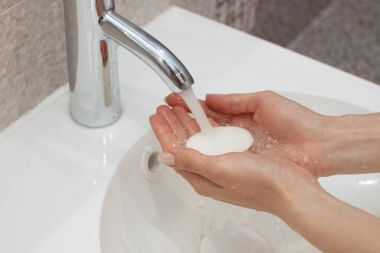 Suyun altında sabunla ellerini yıkamak.