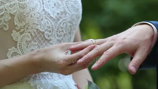 Brudgummen placerar ringen på brudens hand. — Stockvideo