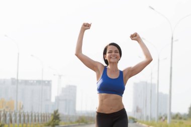 Açık mavi gökyüzüne karşı bitiş çizgisini geçen genç bayan sporcunun düşük açılı görüntüsü