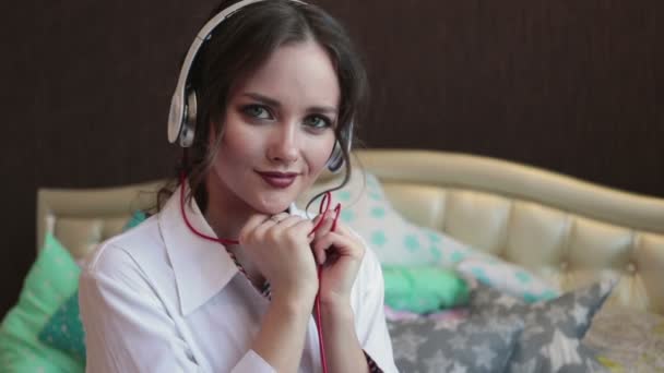 Gelukkig meisje luisteren muziek in witte koptelefoon en glimlachen — Stockvideo
