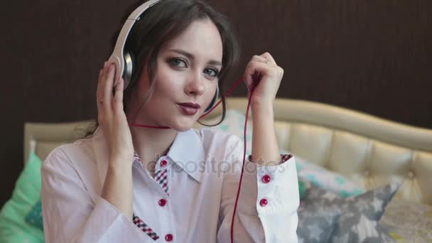 Щаслива дівчина слухати музику в білих навушниках і посміхаючись — стокове відео