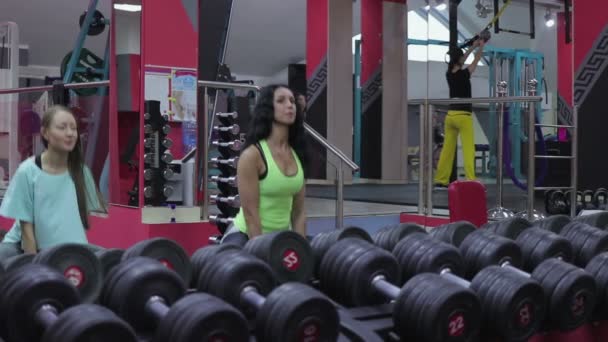 Twee meisjes squat met gewichten bij de fitness room — Stockvideo