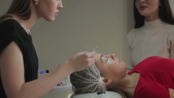 Beautiful young girl admires eyelashes, which her build-up in a beauty salon — Stock Video