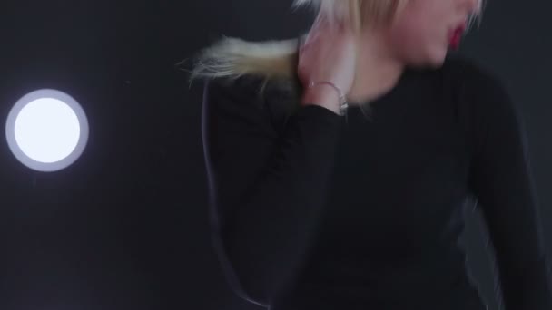 Girl in black dancing against the wall with a spotlight. — Stock Video