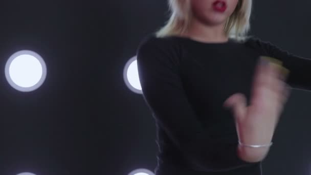 Girl in black dancing against the wall with a spotlight. — Stock Video