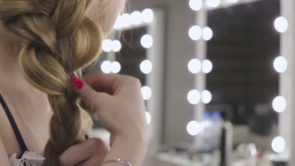 Mooi meisje bindt haar haren in pigtails, schoonheid zorg concept, beauty concept. — Stockvideo