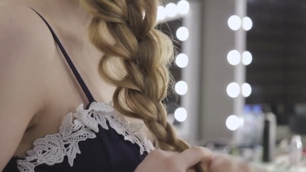 Mooi meisje bindt haar haren in pigtails, schoonheid zorg concept, beauty concept. — Stockvideo