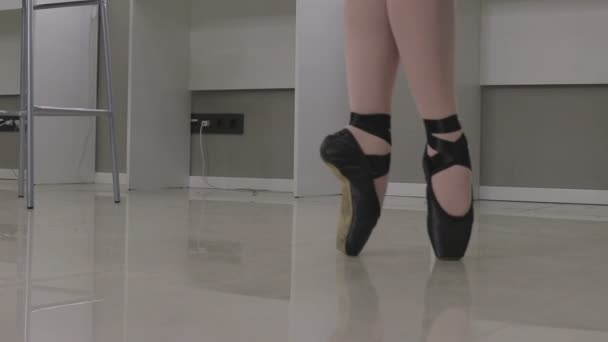 View of a ballerina standing en pointe on the tips of her toes in a pair of ballet shoes — Stock Video