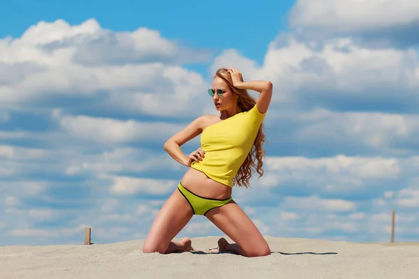 Спокуслива жінка в стильному купальнику на колінах у піску — стокове фото