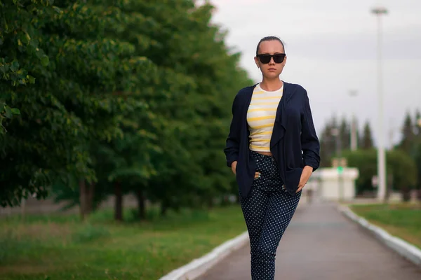 Confiant ajustement jeune femme en lunettes de soleil sur la passerelle dans le parc — Photo