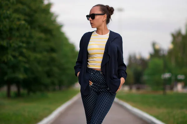 Confident fit young woman in sunglasses on walkway in park — 스톡 사진