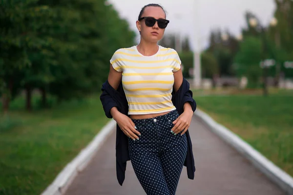 Självsäker passad ung kvinna i solglasögon på gångväg i parken — Stockfoto