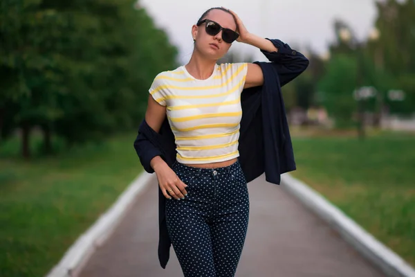 Confident fit young woman in sunglasses on walkway in park — 스톡 사진