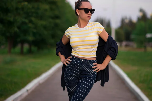 Zelfverzekerde pasvorm jonge vrouw in zonnebril op loopbrug in park — Stockfoto