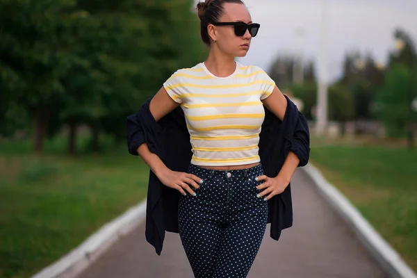 Confiant ajustement jeune femme en lunettes de soleil sur la passerelle dans le parc — Photo