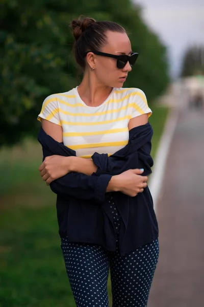 Fiduciosa in forma giovane donna in occhiali da sole sulla passerella nel parco — Foto Stock