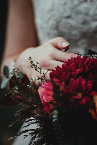 Mariée tenant bouquet avec des fleurs vineuses en composition avec des herbes vertes et brunes — Photo