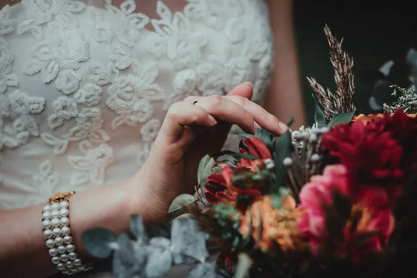 Mariée tenant bouquet avec des fleurs vineuses en composition avec des herbes vertes et brunes — Photo