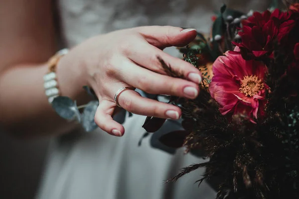 Mariée tenant bouquet avec des fleurs vineuses en composition avec des herbes vertes et brunes — Photo