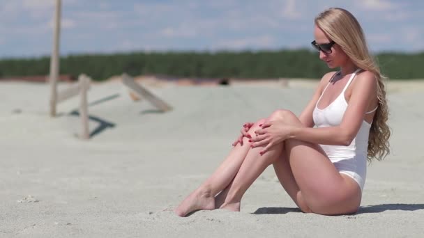 Urocza kobieta siedzi na plaży i sprawia, że ciało macha — Wideo stockowe