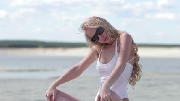 Charmante vrouw zitten op het strand en het maken van body wave — Stockvideo