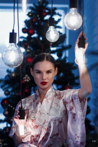 若いです女性に対して電球クリスマスツリー — ストック写真