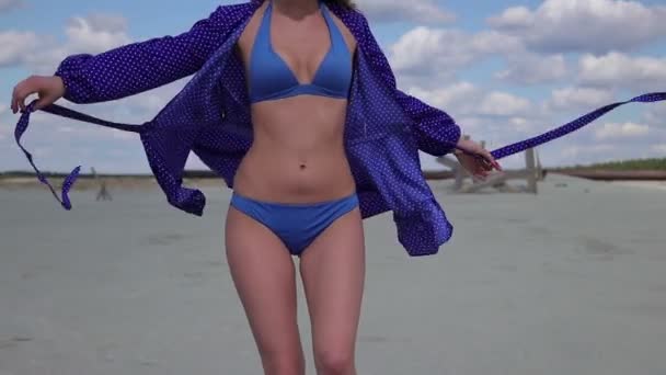 Jeune femme marchant levant la main et tournant en maillot de bain élégant léger — Video