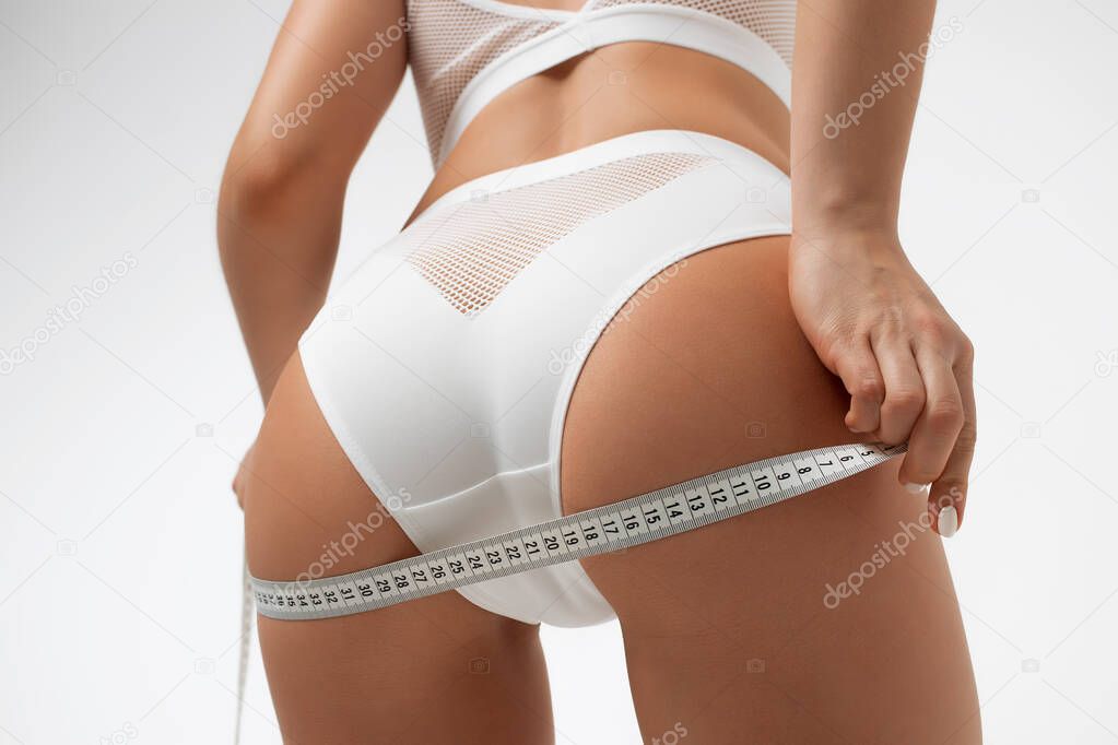 Faceless sexy woman measuring hips with roulette