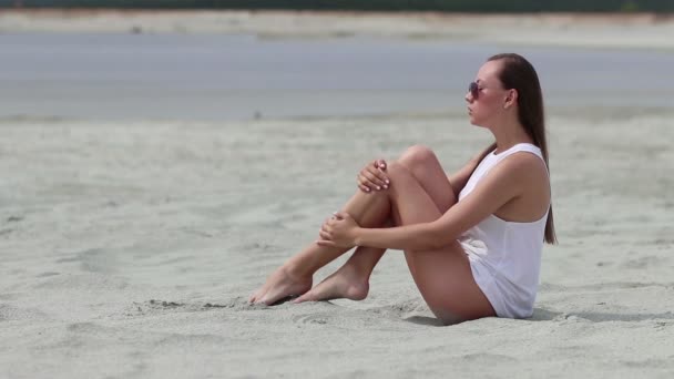 Žena se zkříženýma nohama na písku při dotyku s kůží — Stock video