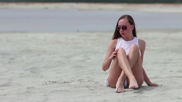 Languid femme assise jambes croisées sur sable toucher la peau — Video