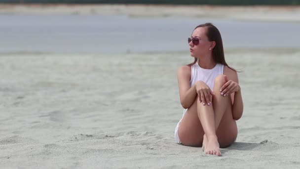 Languid femme assise jambes croisées sur sable toucher la peau — Video