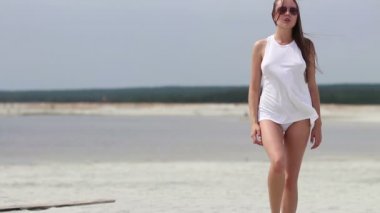 Sıcak kadın ingratiatingly kum üzerinde parmak üzerinde yürüyüş