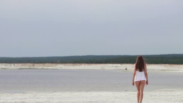 Sensual mujer caminando a lo largo de la playa de puntillas mostrando trajes de baño — Vídeos de Stock