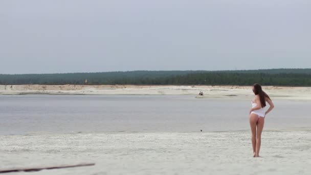 Sensual mujer caminando a lo largo de la playa de puntillas mostrando trajes de baño — Vídeos de Stock