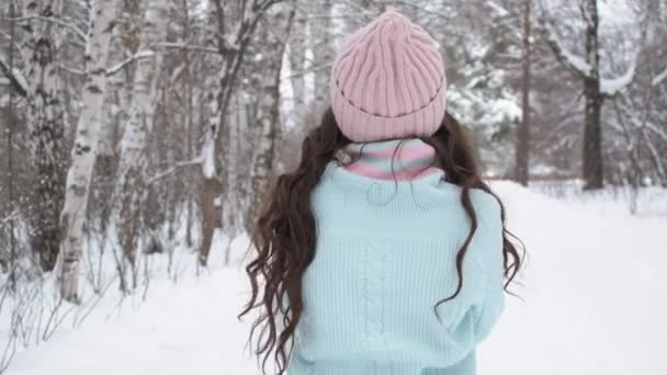 Stijlvolle jonge vrouw op weg naar winterbos — Stockvideo