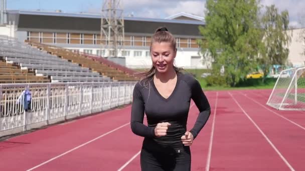 Schlanke, verschwitzte Frau läuft auf Sportplatz — Stockvideo